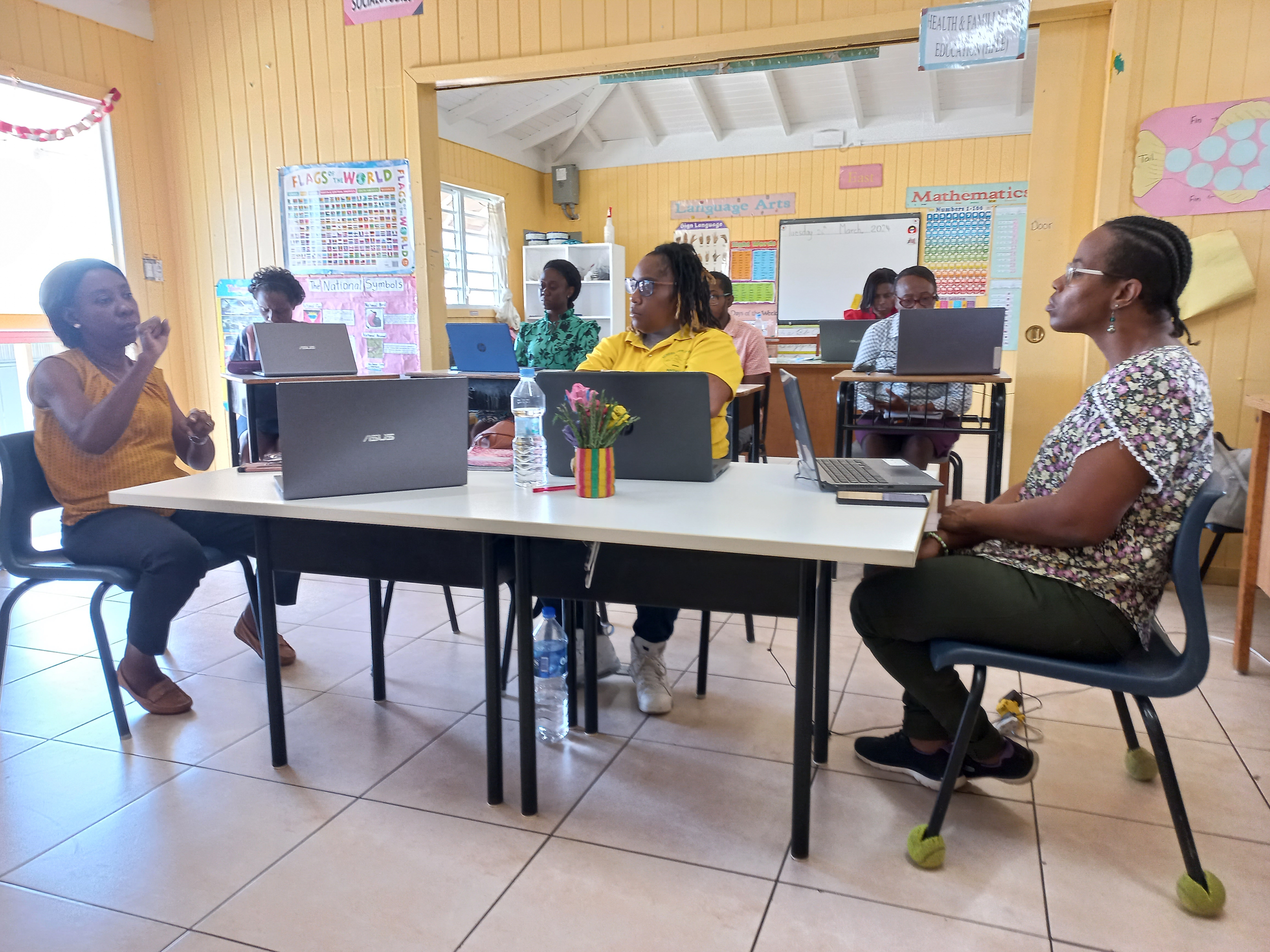 Principal, Mrs. Patricia Archibald sits at a desk interpreting in sign language to two staff members at the School for the Deaf in Antigua and Barbuda.